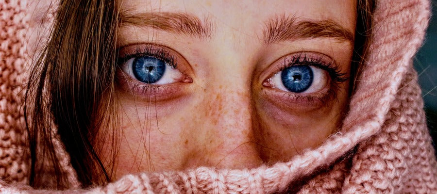 closeup of woman's face and large blue eyes wrapped up in pink knitwear