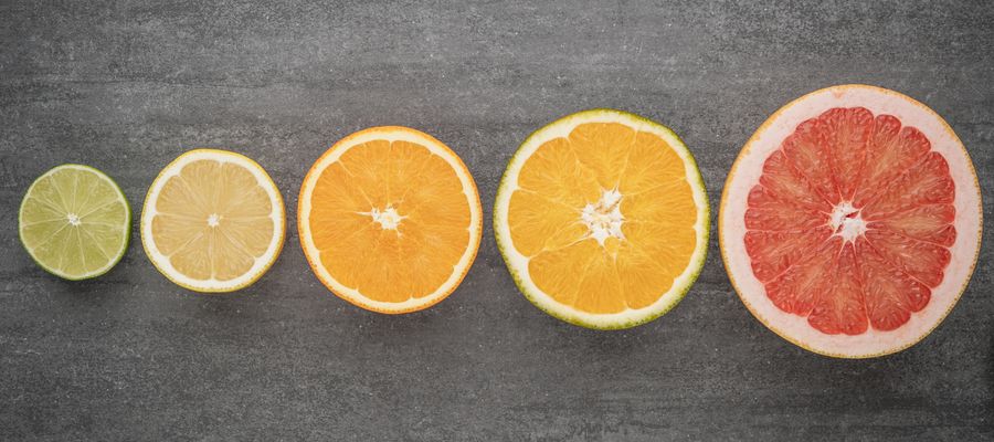 lime, lemon, orange, grapefruit citrus slices against gray wooden background