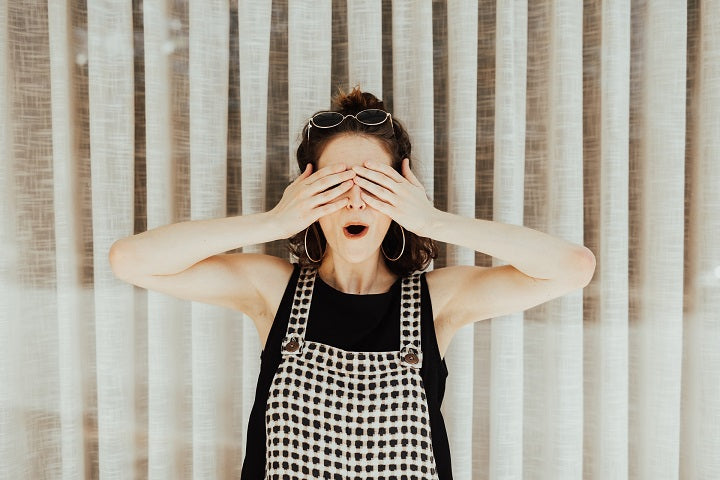 woman in checkered overalls covering eyes