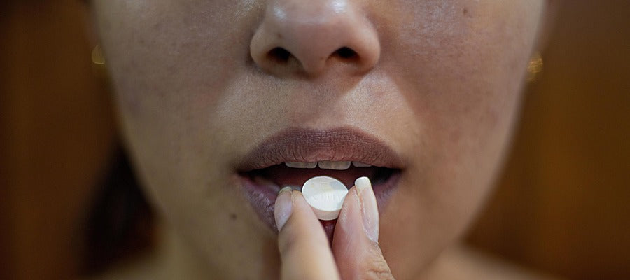 closeup of woman taking pill to her open mouth
