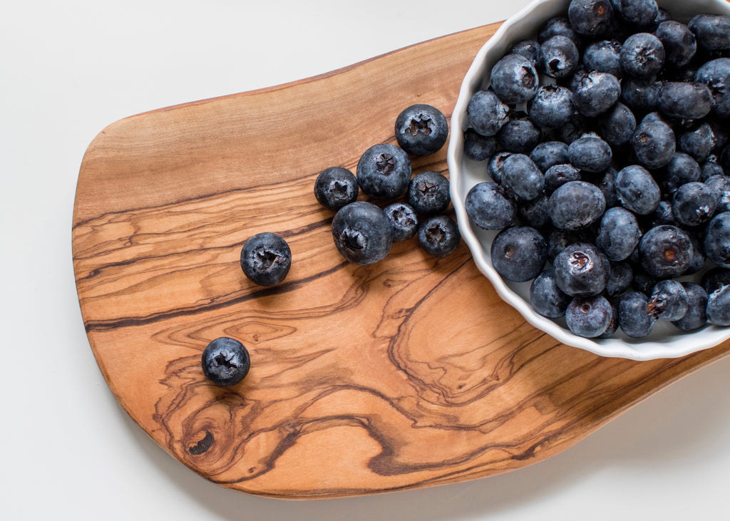 blueberries in white bowl and on gray white surface