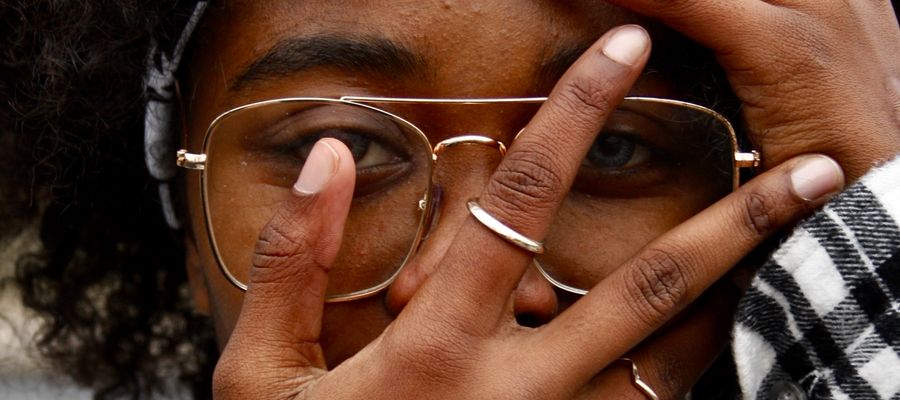 African-American woman with eyeglasses partly covering her eyes with her fingers