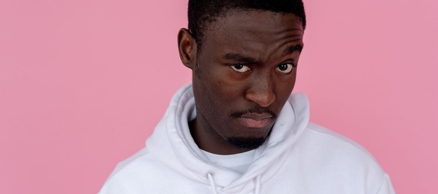 black man in white hoodie against pink background with wondering expression