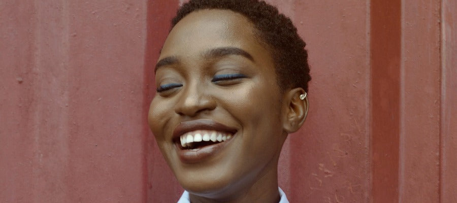 portrait of a black woman with short hair laughing with eyes closed